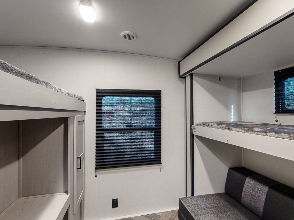 Bunkhouse Cozy room with bunk beds, a window, and a sofa against white walls.