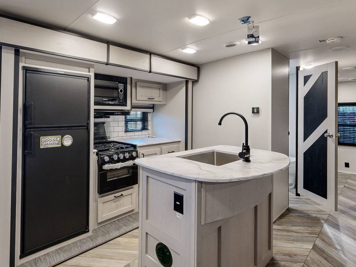 Fully Equipped Kitchen Modern kitchen interior in an RV with an island, stove, and refrigerator.