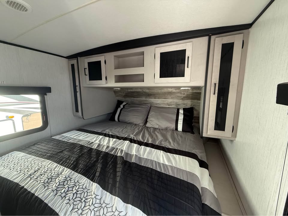 Primary Bedroom Cozy bedroom with a bed, gray comforter, and white cabinetry above.