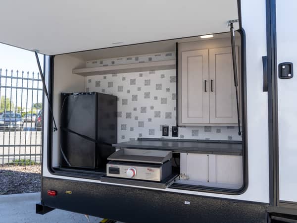 Outdoor Kitchen Outdoor kitchen setup with a grill, fridge, and cabinets inside a camper.